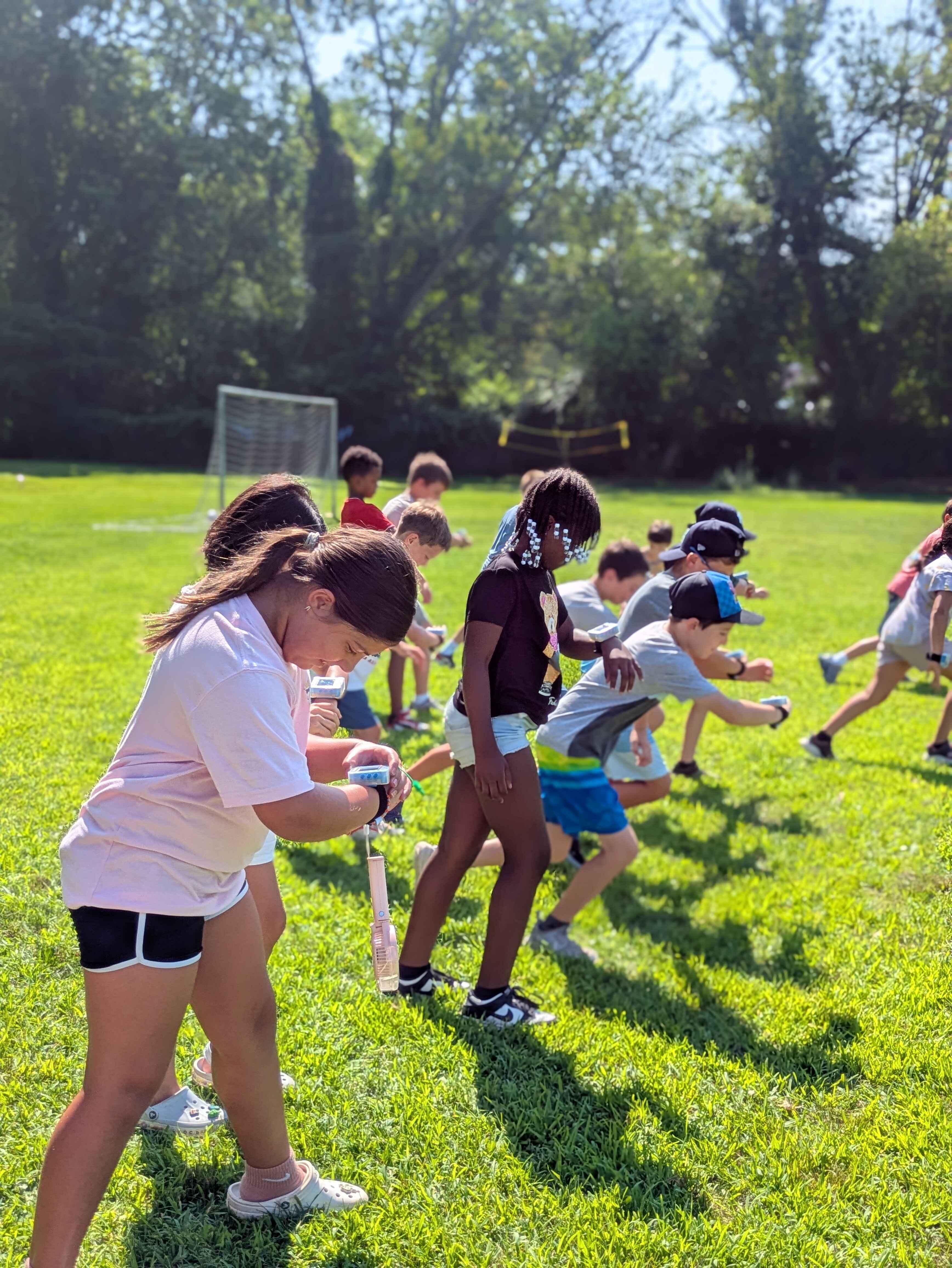 A group of children looking down at their ZTAG watches while playing a game of red-light-green-light. 