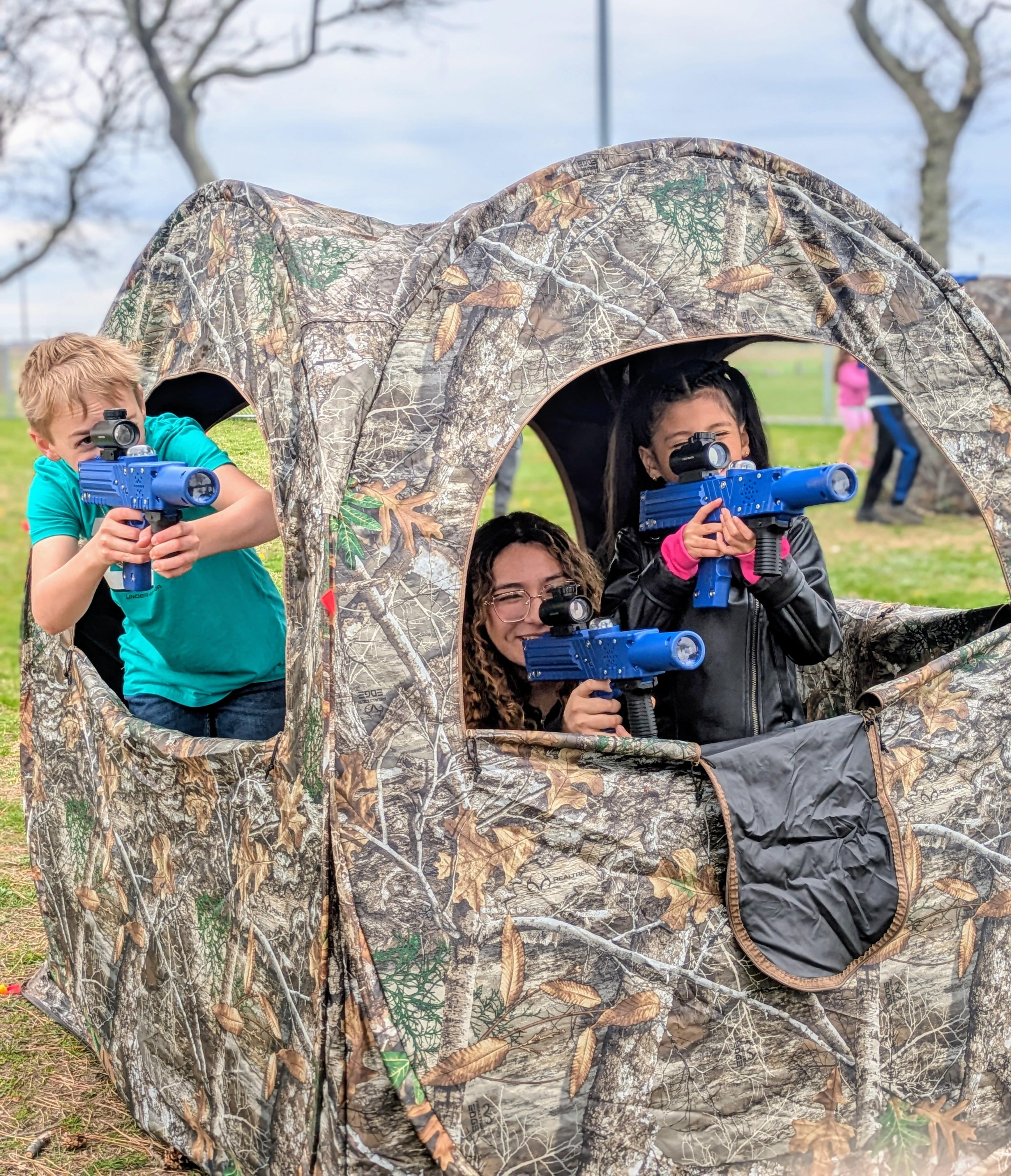 A group of laser blue laser tag team members aiming outside of their hunting blind.