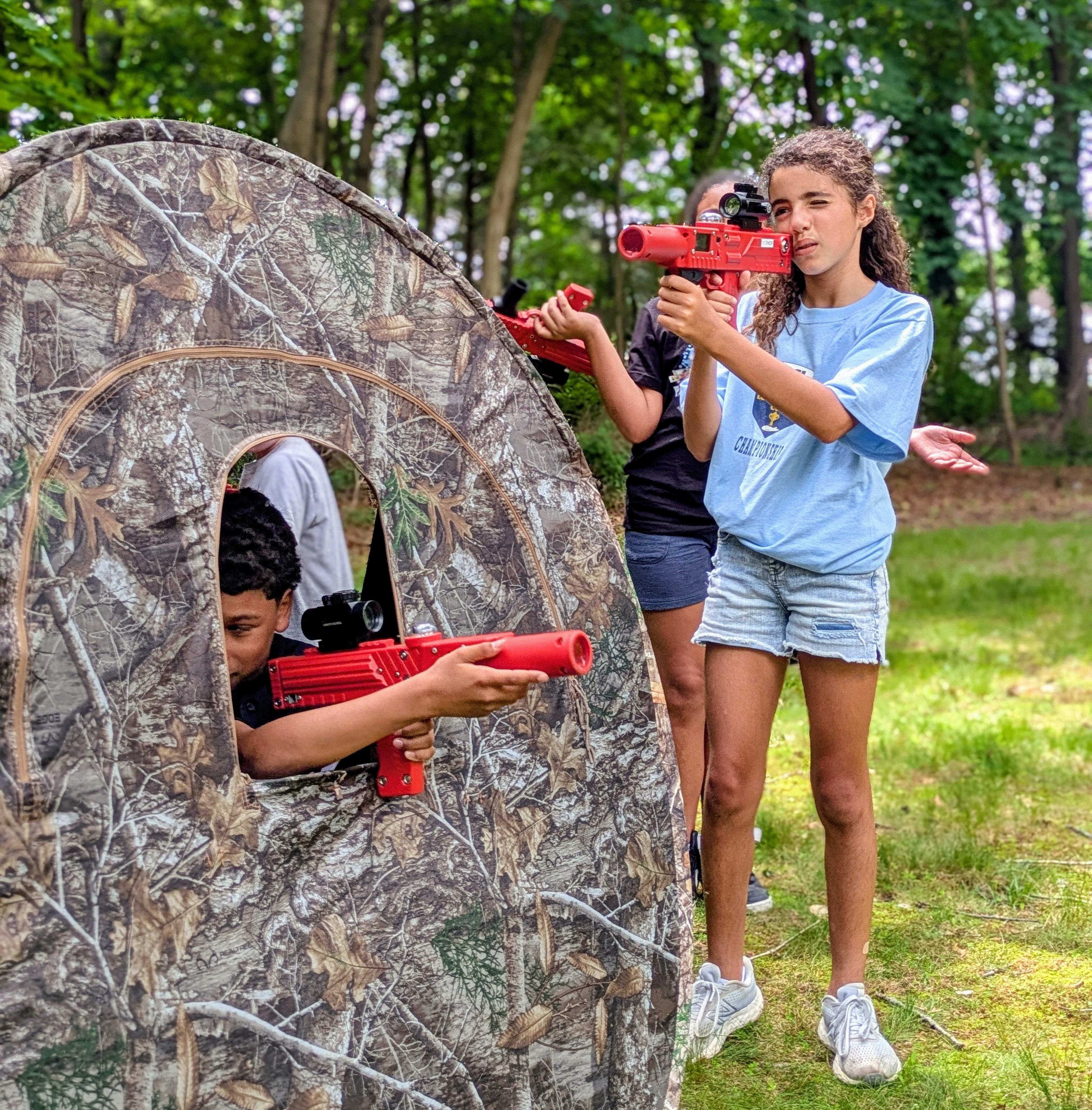 A group of red team laser tag members taking aim outside of their hunting blind.